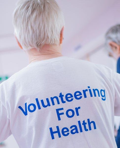 Back view of an elderly person wearing a t-shirt that reads "Volunteering For Health."