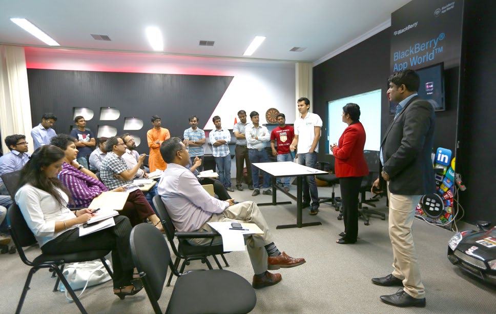 Professionals attending a presentation or training session in a room branded with BlackBerry App World.