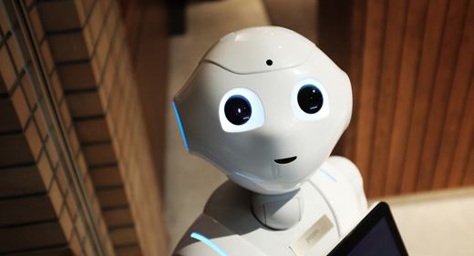 Close-up of a white Pepper robot with glowing eyes holding a tablet.