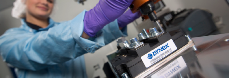 Scientist in a lab coat and purple gloves meticulously working on industrial equipment that features a Dynex brand label.