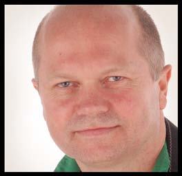 Close-up portrait of a man with blue eyes and light skin, slightly smiling, wearing a green shirt.
