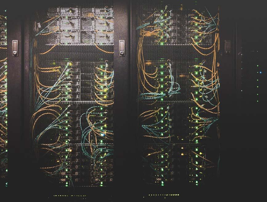 Close-up of server racks with illuminated components and numerous yellow and blue network cables, illustrating data center infrastructure.