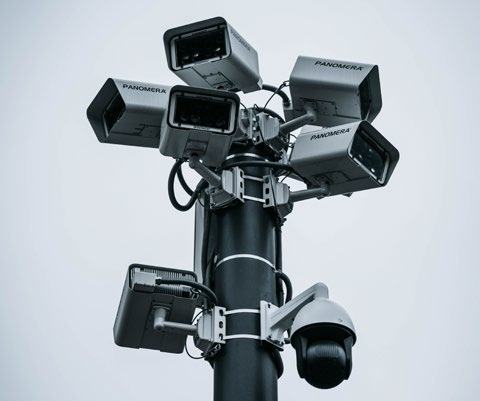 Security pole with multiple 'PANOMERA' cameras and a dome camera, illustrating a surveillance system setup.