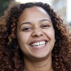 Headshot of a smiling woman with curly brown hair.