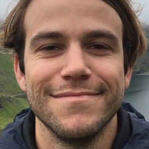 Close-up portrait of a smiling man with a natural outdoor background.