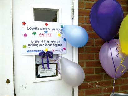 Sign announcing £50,000 available for Lower Green ideas, decorated with balloons.