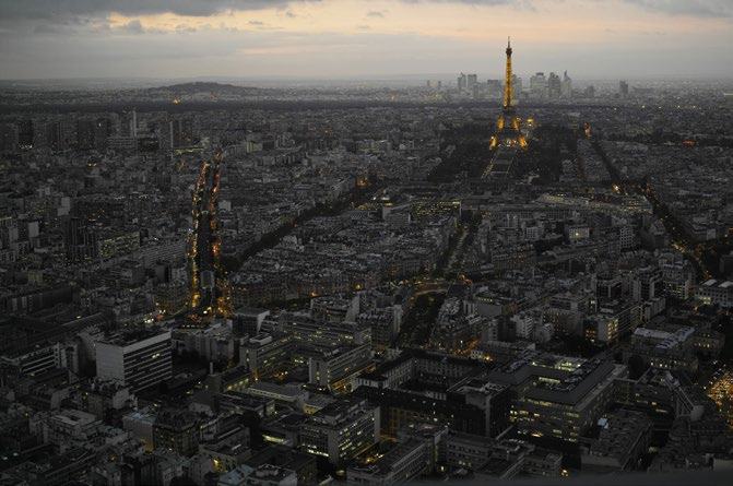 Aerial view of the city of Paris at dusk, with the Eiffel Tower brightly lit.