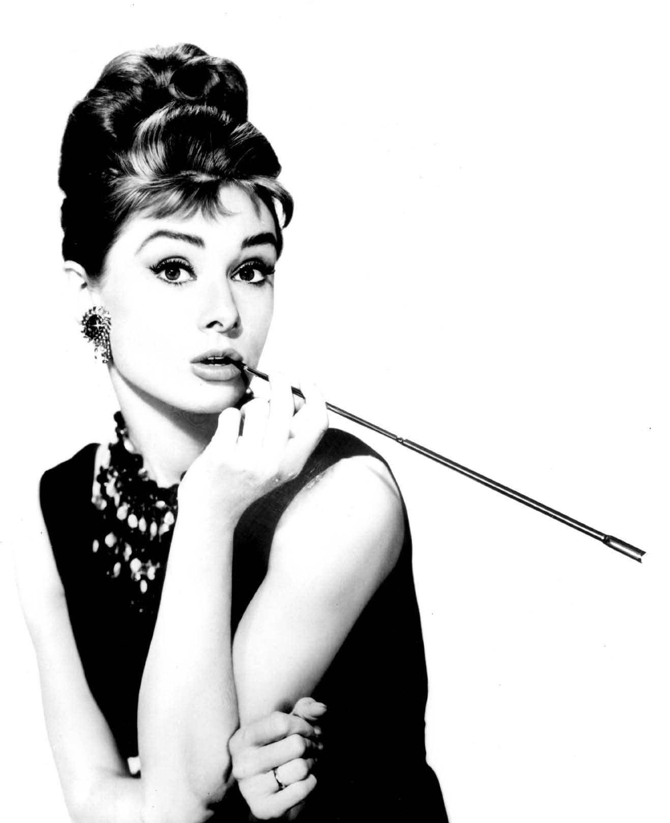 Black and white photo of Audrey Hepburn looking surprised, holding a cigarette holder.