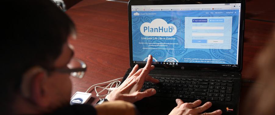 A person typing on a laptop displaying the login page for "PlanHub", a website for life planning with options for social media or email login.
