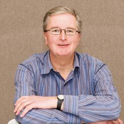 Headshot of a smiling man in glasses and a blue striped shirt, with his arms crossed.