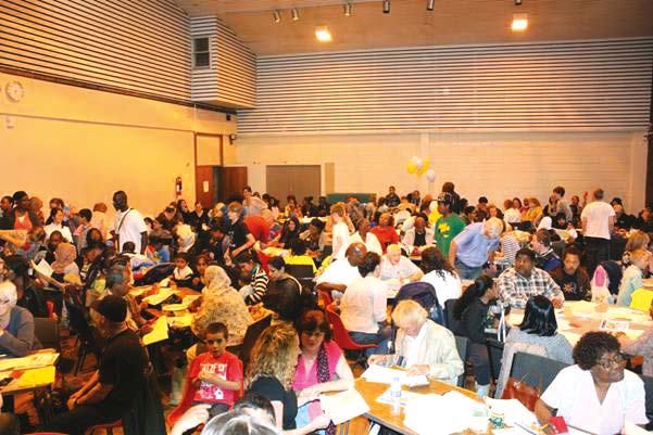 Large hall filled with diverse people seated at tables during a community event or meeting.