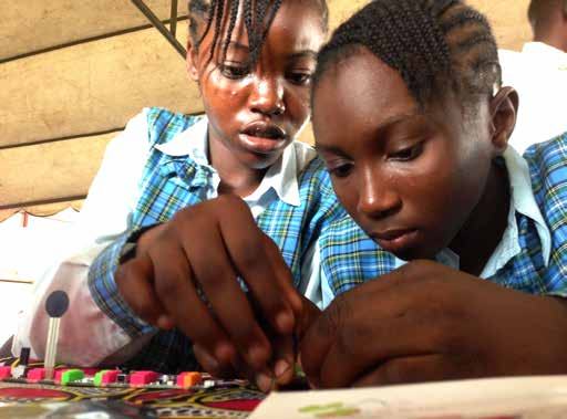 Two young girls engaged in hands-on learning, assembling or interacting with small colorful electronic components on a table.