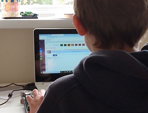 A person seen from behind, working on a laptop displaying what appears to be an online learning or assignment interface.