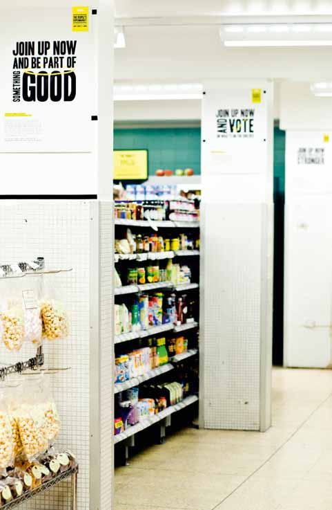 Interior view of a supermarket aisle with product shelves and promotional posters on the walls reading "JOIN UP NOW" messages.
