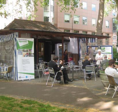 Outdoor cafe scene with people at tables, featuring a prominent banner for "Bloomsbury Squared" and other promotional materials.
