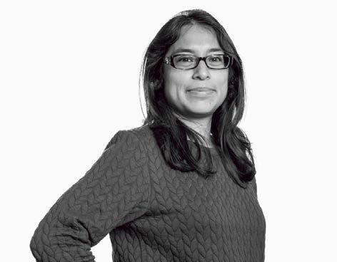 Black and white portrait of a woman with long dark hair and glasses, smiling faintly.