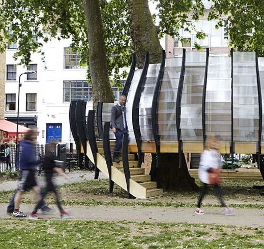 Modern, translucent structure with slatted walls built around trees in a park, with people walking by and buildings in the background.