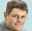Headshot of a man with glasses and short brown hair, looking slightly to the side.
