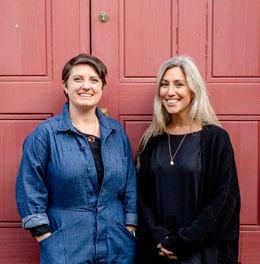 Two women, possibly team members, smiling in front of a red door.