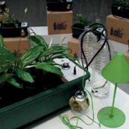 A close-up of potted plants, part of an automatic watering system with sensors, water bottles, and a green lamp.