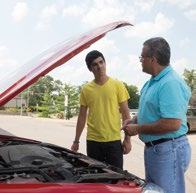 Two men looking at the open hood of a car, examining the engine, possibly discussing a repair.