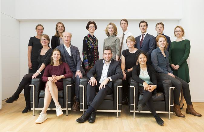 A group photo of fifteen business professionals, both men and women, posing in an indoor setting.