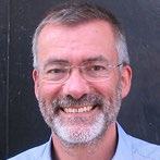 Headshot of a smiling middle-aged man with a beard and glasses.
