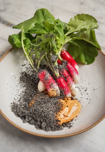 Plated dish featuring fresh radishes with green tops, black sesame seeds, and an orange sauce.