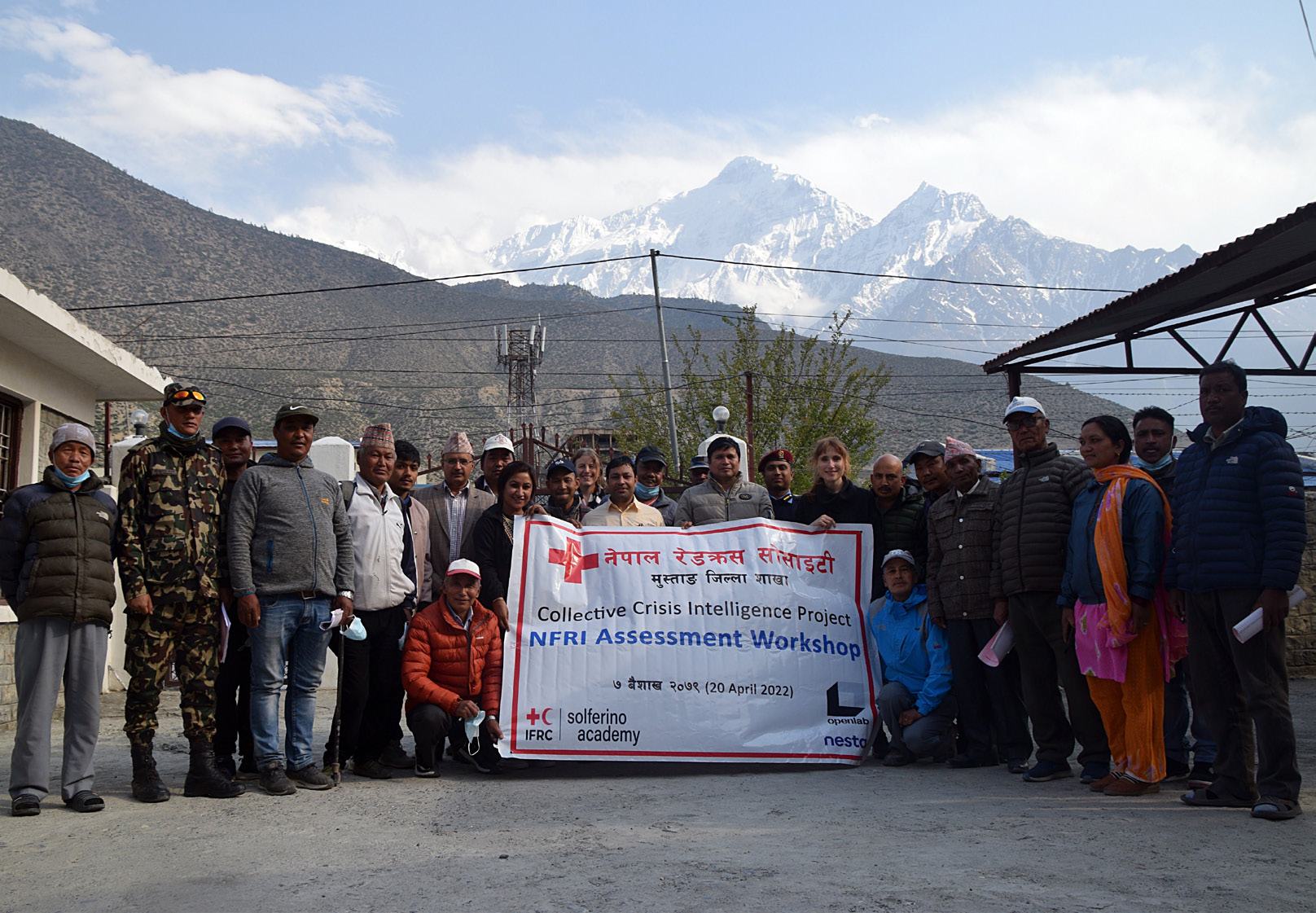 Group photo of people holding a banner for the "Collective Crisis Intelligence Project, NFRI Assessment Workshop" in front of mountains.