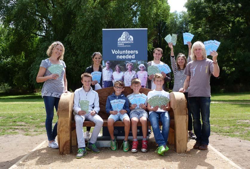 A group of adults and children holding leaflets and standing near a bench, with a "Bournemouth Parks Foundation Volunteers needed" banner.