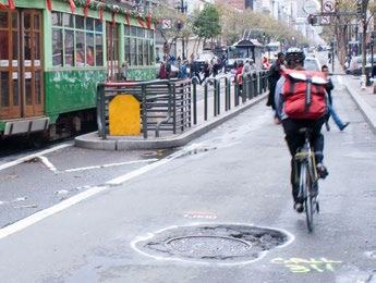 A cyclist rides past a large pothole and a tram on a city street, with 'CALL 311' written on the pavement.