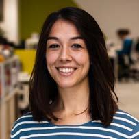 Headshot of a woman with dark hair, a striped shirt, and a bright smile.