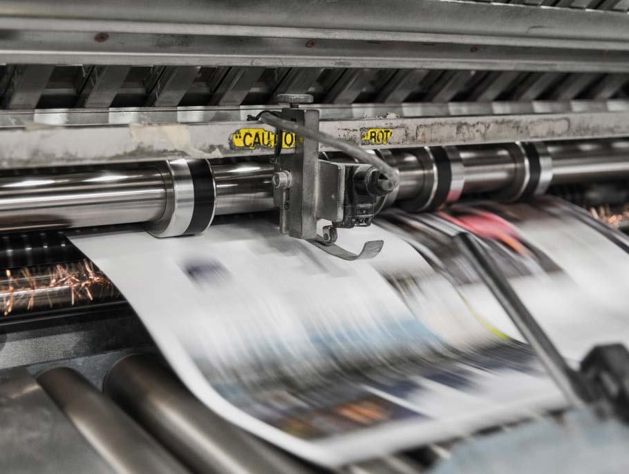 Close-up of paper moving rapidly through the rollers of a printing press, illustrating the high-speed printing process.