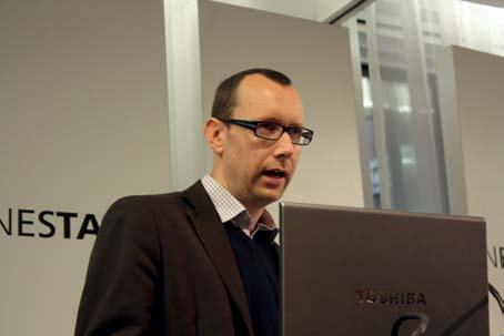 Man in glasses speaking at a Nesta event, with a Toshiba laptop in front of him.