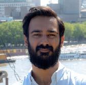 Headshot of a man with a beard and dark hair looking towards the viewer.
