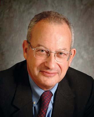 Portrait of an older man with glasses wearing a suit and tie, smiling slightly.