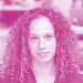 Headshot of a smiling woman with long curly brown hair.