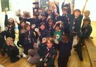 A group of children, possibly scouts, proudly hold up badges or awards they have received.