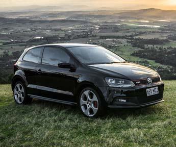 A black Volkswagen Polo GTI car parked on a grassy hill with a scenic landscape in the background.