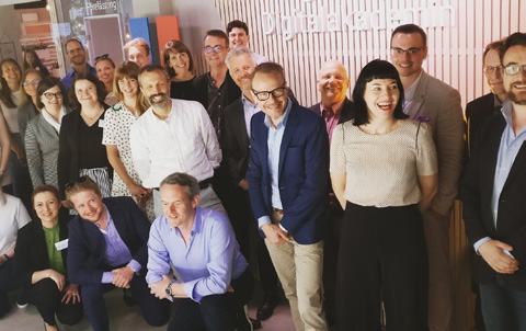 A diverse group of smiling adults poses indoors, likely participants or staff of the 'Digital Academy'.
