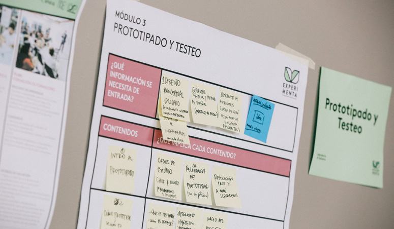 Wall-mounted poster for "Modulo 3 Prototipado y Testeo" showing a table filled with sticky notes containing workshop content and input information.