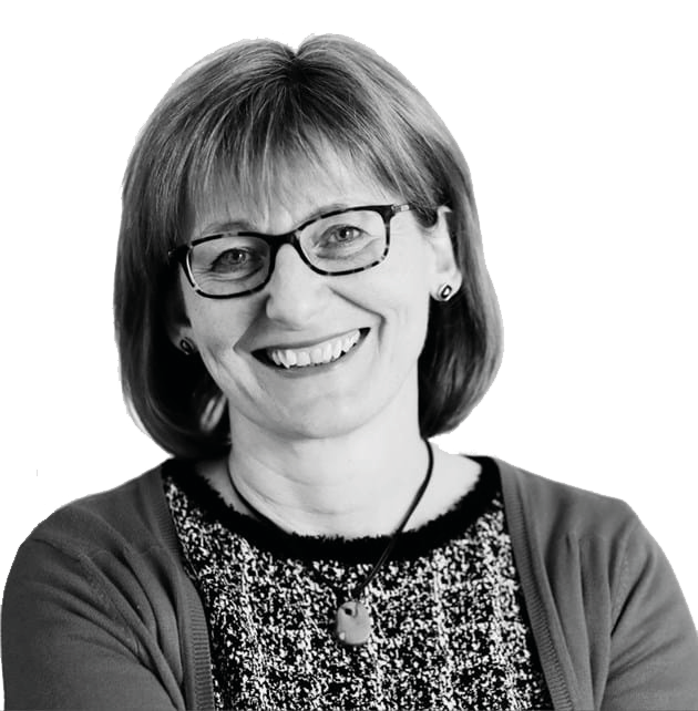 Black and white headshot of a smiling woman with short hair and glasses, wearing a patterned top and cardigan.