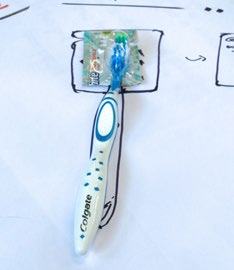 A Colgate toothbrush rests on a white surface, surrounded by sketched lines, possibly illustrating a product concept or design process.