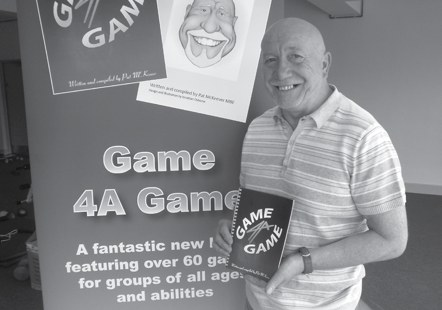Man holding a "Game 4A Game" book next to a promotional banner for the game, showcasing a product.