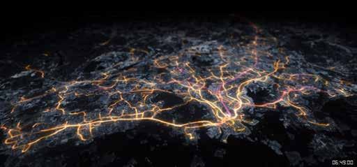 Elevated view of a city at night with glowing yellow and orange lines representing interconnected pathways or a network.