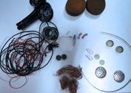 Various disassembled electronic components, including wires, copper, and metal pieces, laid out on a white surface.