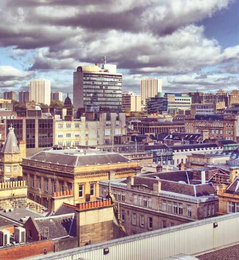 Aerial view of an urban landscape with a mix of old and modern buildings under a cloudy sky, suggesting a city like Glasgow.