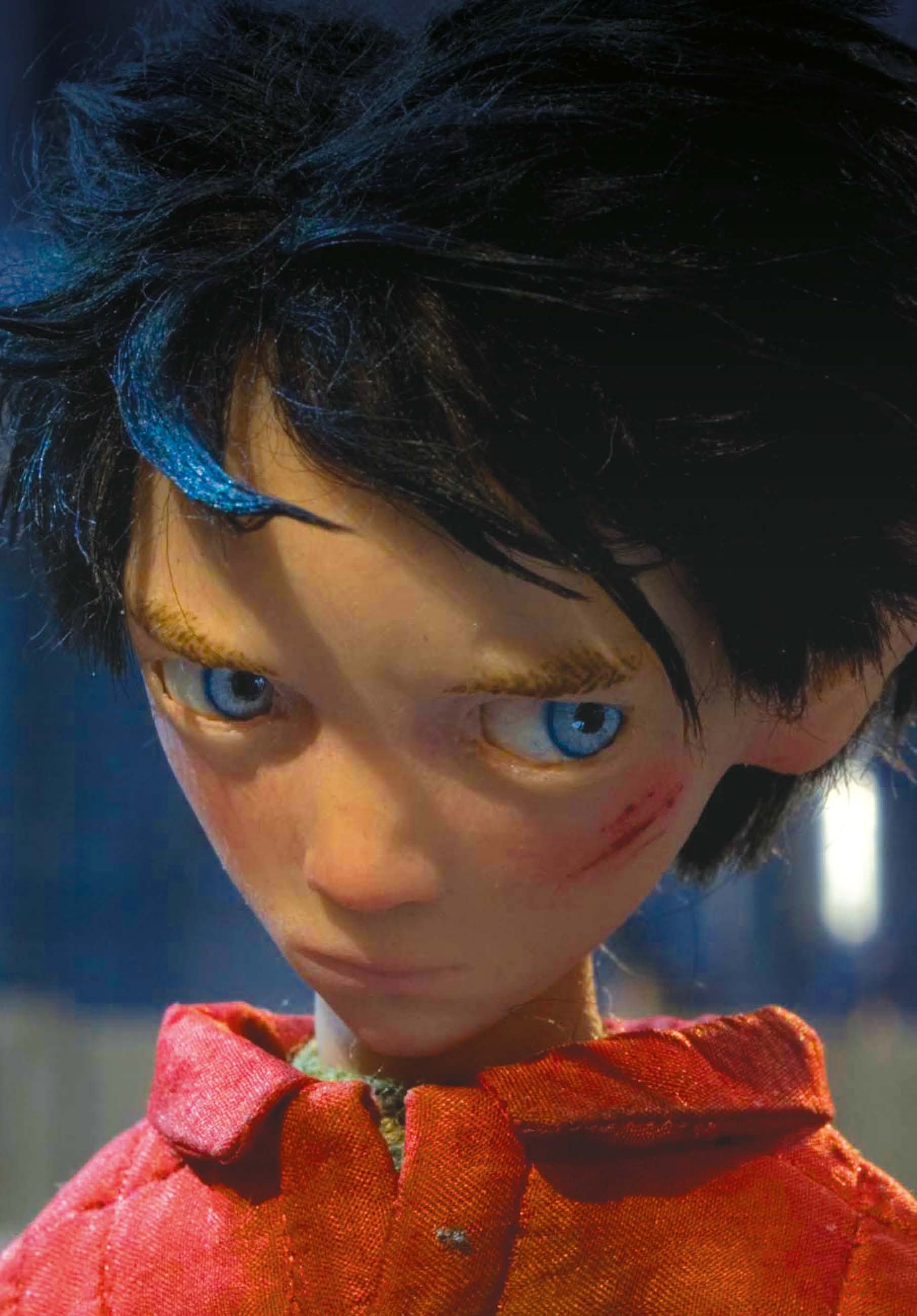 Close-up of a stop-motion animated boy with tousled dark blue hair, large blue eyes, and a red jacket, showing details of his face. Image from 'Peter and the Wolf', directed by Suzie Templeton.