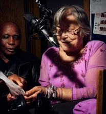 A man and a woman in a recording studio, with a microphone, showing them engaged in recording audio.