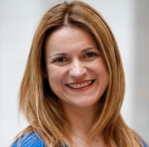 Headshot of a woman with long light brown hair, smiling broadly.